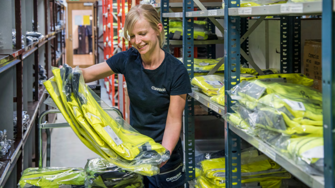 Caverion-medarbetare står på ett lager och packar upp skyddskläder