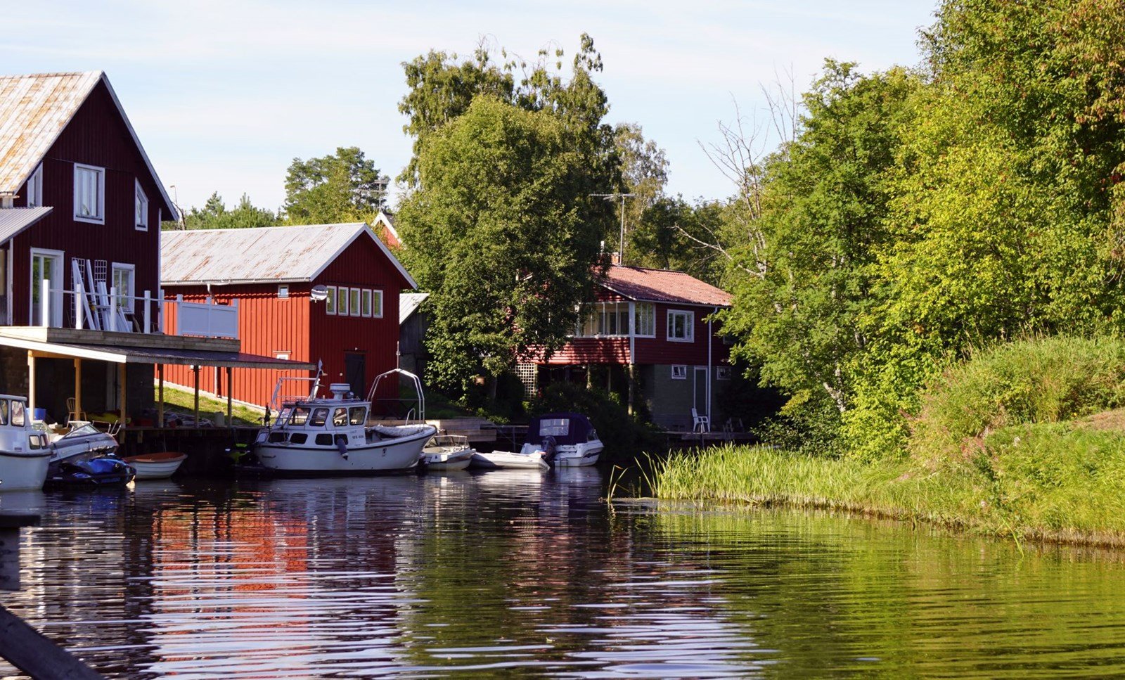 Somrig bild på röda stugor vid Sörfjärden i Nordanstigs Kommun