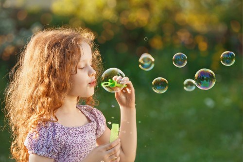 Little girl blowing soap bubbles outdoors.jpeg